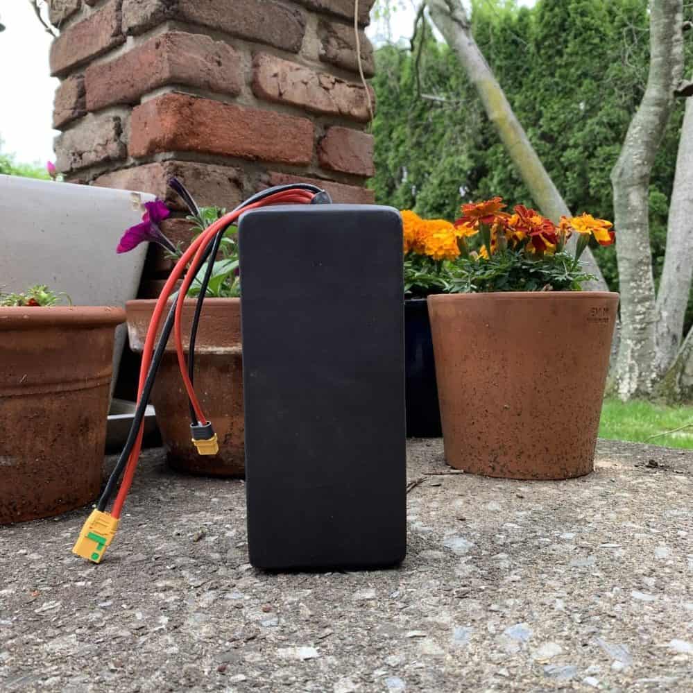 A black box sitting on the ground next to some flowers.