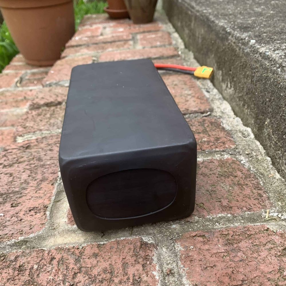 A black box sitting on the ground next to a brick wall.