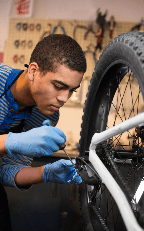 Mechanic repairs bike with tool and gloves.