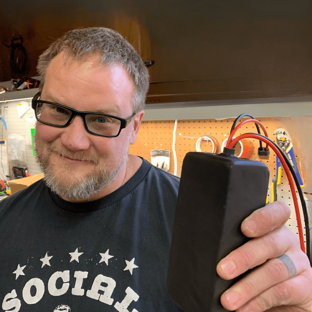 Man holding a black battery pack.